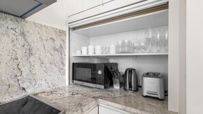 Eine kompakte Küchenzeile mit einer Bosch-Mikrowelle, einer Kaffeemaschine und einem Toaster.