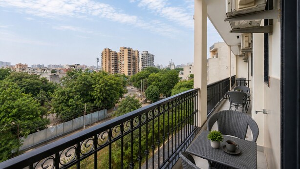 A balcony with a view of a cityscape, including high-rise buildings and greenery. - Urban Alcove Executive Suites by Luxe 8 (Gurugram)