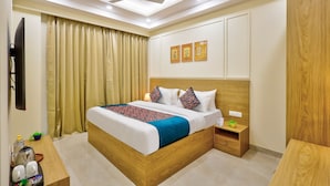 A hotel room with a bed, bedside table, nightstand, and a ceiling fan. - Urban Alcove Executive Suites by Luxe 8 (Gurugram)