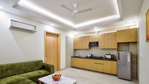 A modern kitchen with wooden cabinets, a built-in microwave, and a stainless steel refrigerator. - Urban Alcove Executive Suites by Luxe 8 (Gurugram)