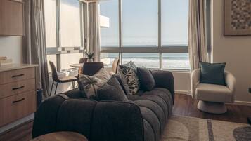A modern living room with a sofa, a dining table, and a view of the sea.