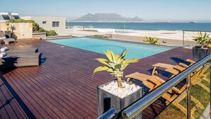 A rooftop pool with a view of the ocean and mountains. - Infinity 2BR Seaside Stay - Steps from Blouberg Beach (Cape Town)