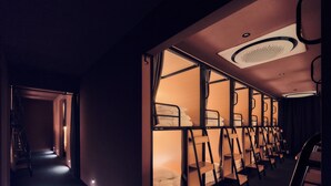 Una camera d'albergo con letti a castello, una scala e un corridoio.