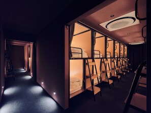A hotel room with bunk beds, a staircase, and a hallway.