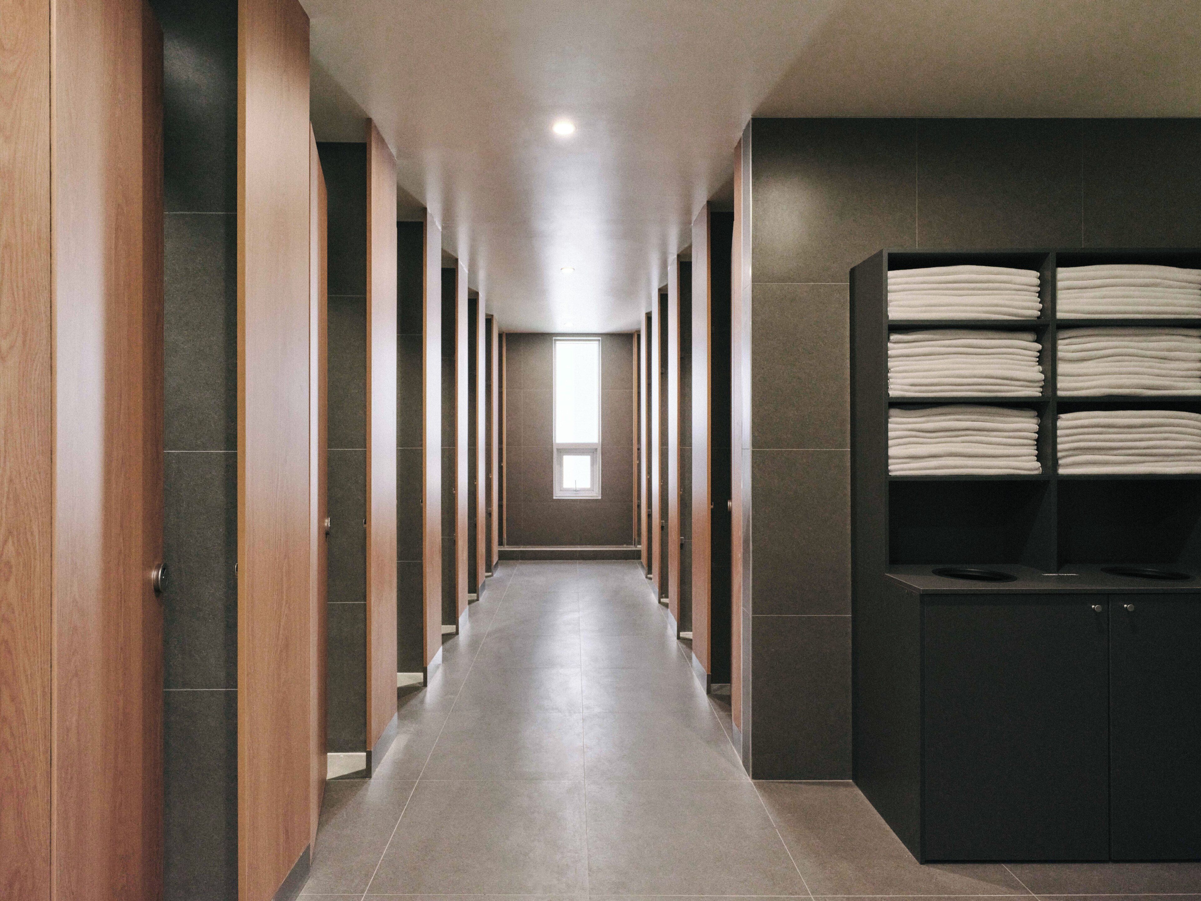 Um corredor com armários de madeira e piso de azulejos, que leva a uma janela.