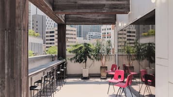 An outdoor terrace with a wooden pergola, seating area with chairs, and potted plants.