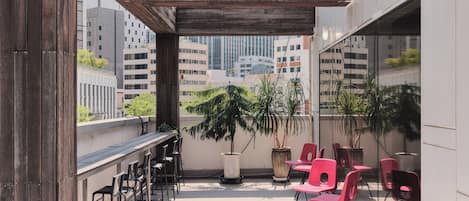 An outdoor terrace with a wooden pergola, seating area with chairs, and potted plants.