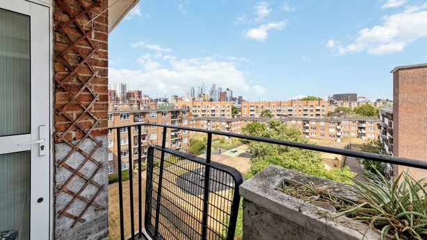 A balcony with a view of a residential area, including brick buildings and a clear sky. - Airy 1BD Flat with Balcony, Battersea (Greater London)