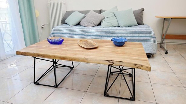 A room with a bed, a wooden table with metal legs, and a radiator. - Pantheon - A Cozy Nest in the Center of Athens (Athina)