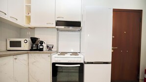 A compact kitchen with a microwave, coffee maker, and a stove. - Pantheon - A Cozy Nest in the Center of Athens (Athina)