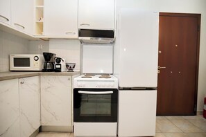 Cozinha compacta com micro-ondas, cafeteira e fogão.