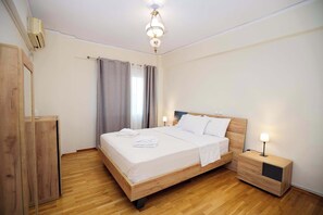 Ein Hotelzimmer mit einem hölzernen Bett, einem Nachttisch, einem Kleiderschrank und einer Kristallleuchter.