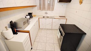 Eine kompakte Küche mit Mikrowelle, Kaffeemaschine, Spüle und kleinem Kühlschrank.