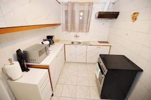 Eine kompakte Küche mit Mikrowelle, Kaffeemaschine, Spüle und kleinem Kühlschrank.