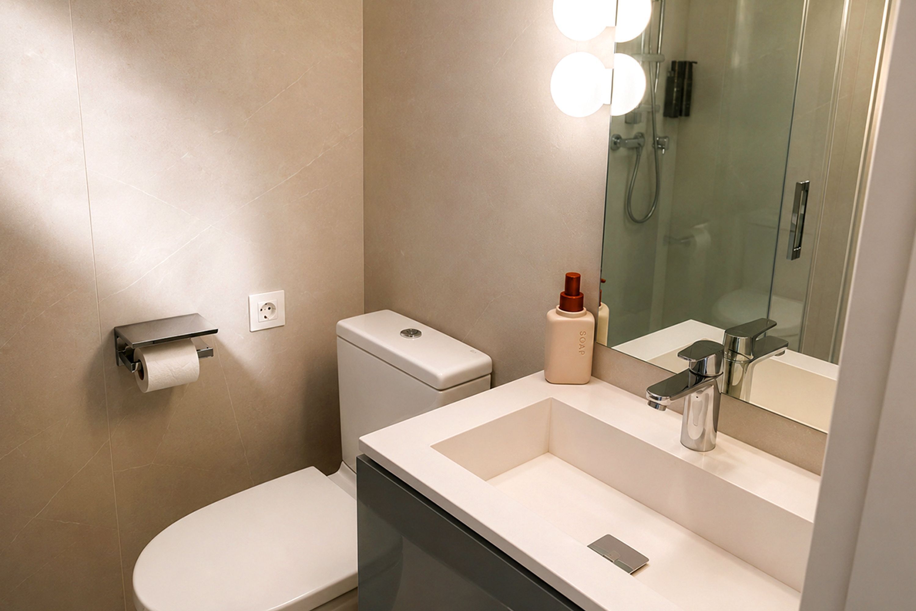 Un baño moderno con inodoro, lavamanos y espejo.