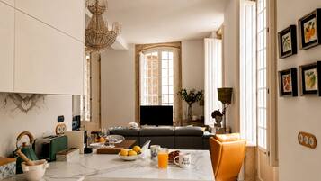 A modern kitchen with a marble countertop, a dining area with a sofa, and a chandelier.