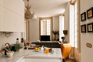 Eine moderne Küche mit Marmorarbeitsplatte, eine Essecke mit einer Couch und einem Kronleuchter.