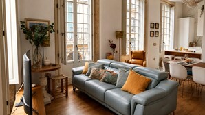 A modern living room with a sofa, a dining table, and a television. - Genteel Home Casa Leal de Ibarra (Almeria)
