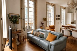 Ein modernes Wohnzimmer mit Sofa, Esstisch und Fernseher.