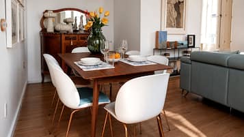 A dining area with a wooden table, white chairs, and a vase with yellow flowers.