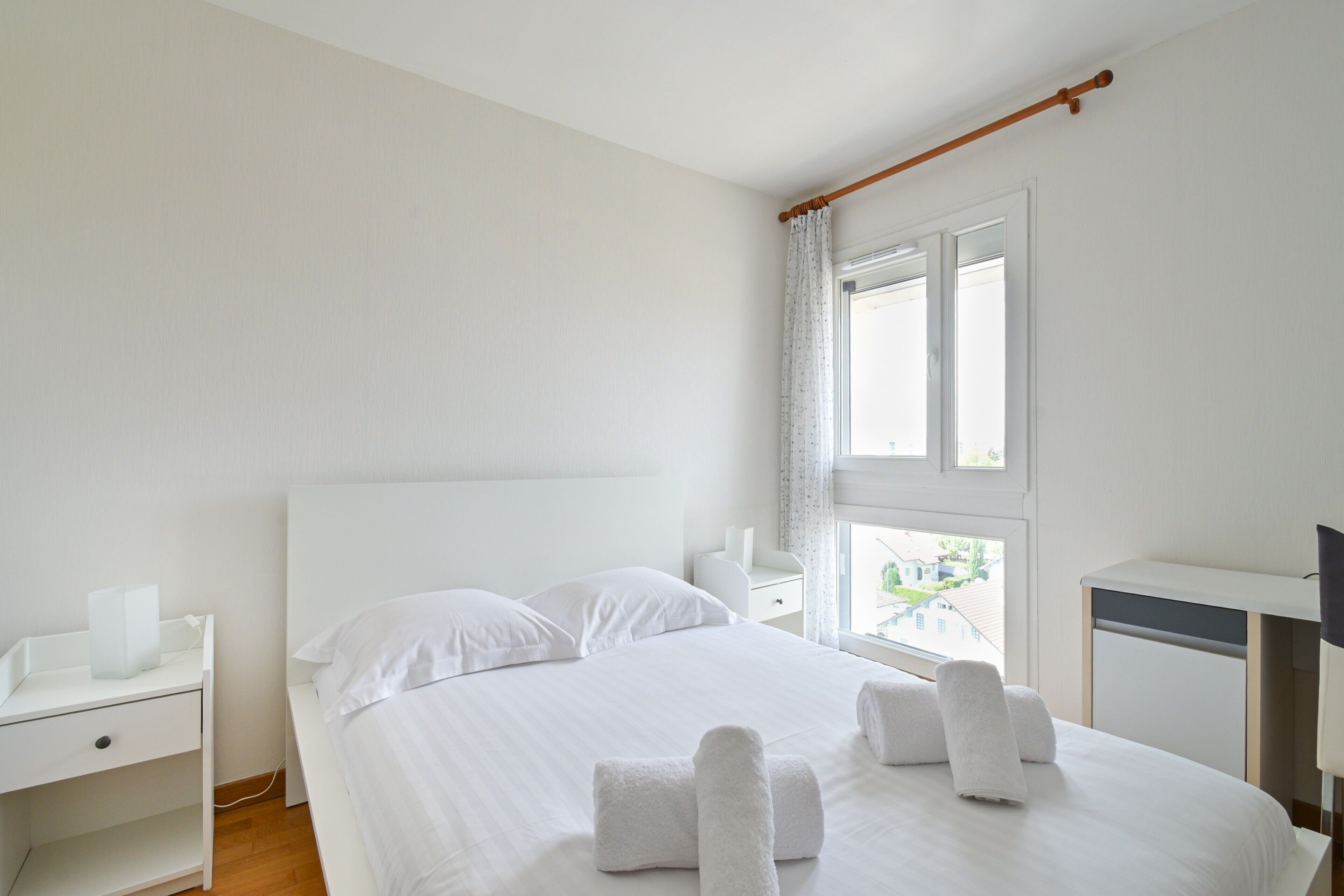 A hotel room with a bed, a desk, and a window.