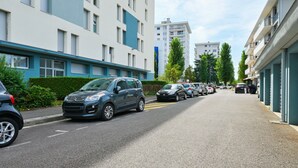 Eine Wohnstraße mit parkenden Autos, modernen Mehrfamilienhäusern und einem klaren Himmel.
