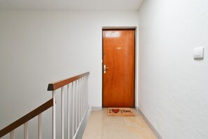 A narrow hallway with a wooden door at the end, a white railing on the left, and a doormat with 'I ♥ Home' on the floor. - Spacious T4 Apartment with Mountain Views, Wi-Fi, and Parking – Sleeps 8 in Annecy (Annecy)