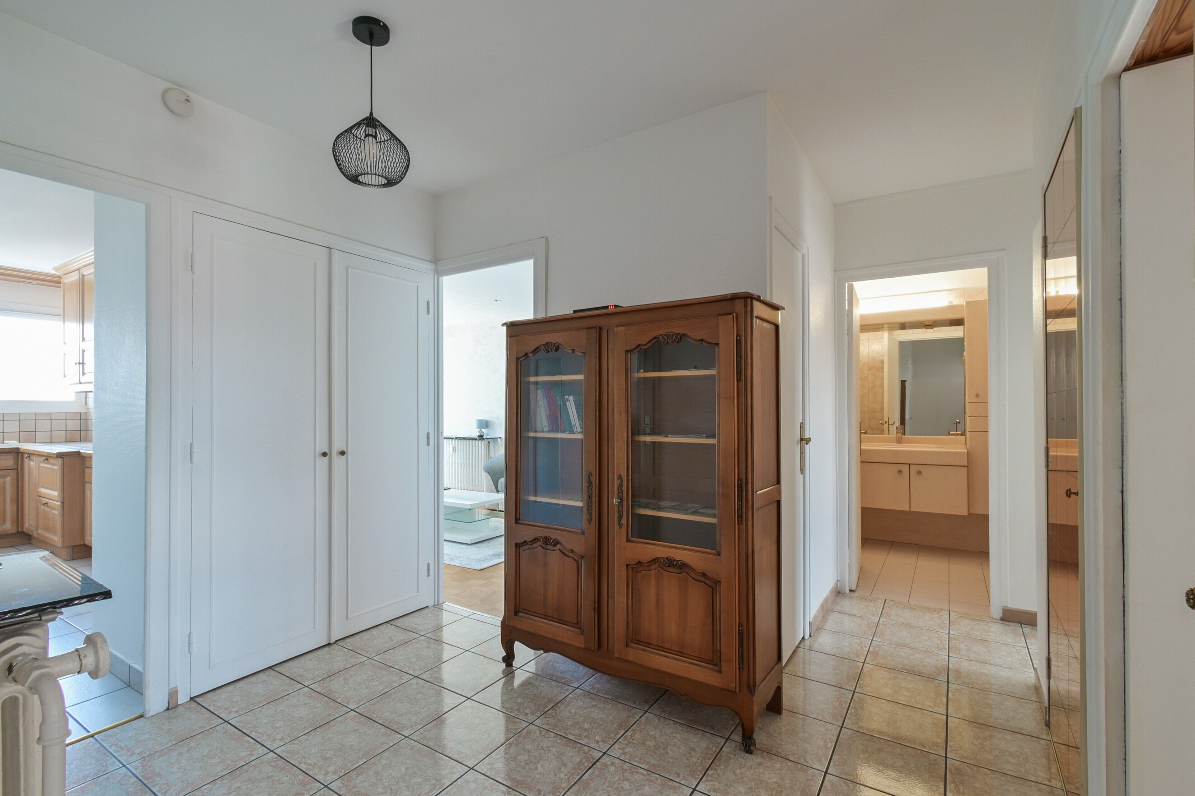 Ein Flur mit einem Holzschrank, weißen Türen und einer Deckenleuchte.