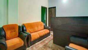 A living room with a sofa, a chair, and a dark wooden cabinet. - Classic Avisi Residency (Bhubaneshwar)