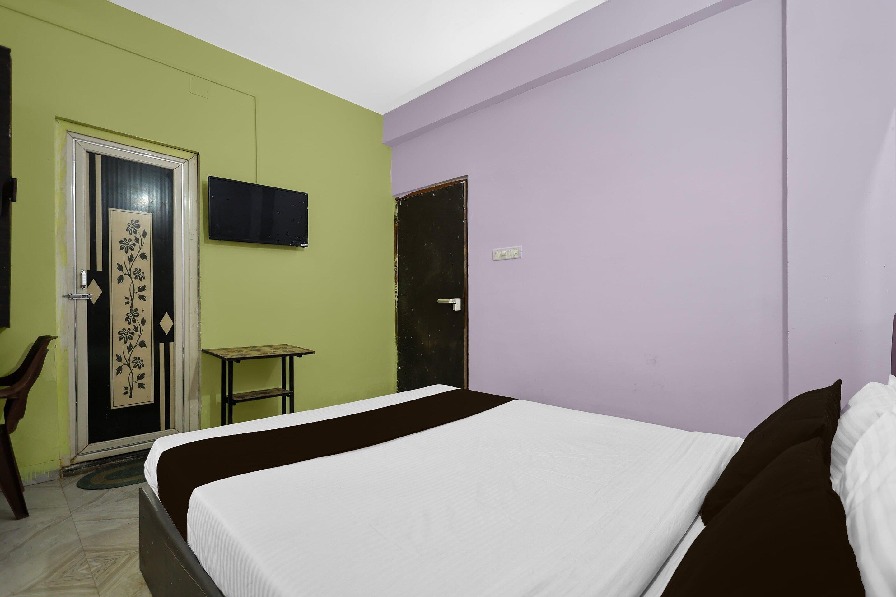 Ein Schlafzimmer mit einem Bett, einem Fernseher, einer Tür und einem kleinen Tisch.