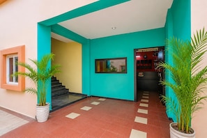 A hallway with a turquoise wall, a staircase, and potted plants. - Classic Avisi Residency (Bhubaneshwar)