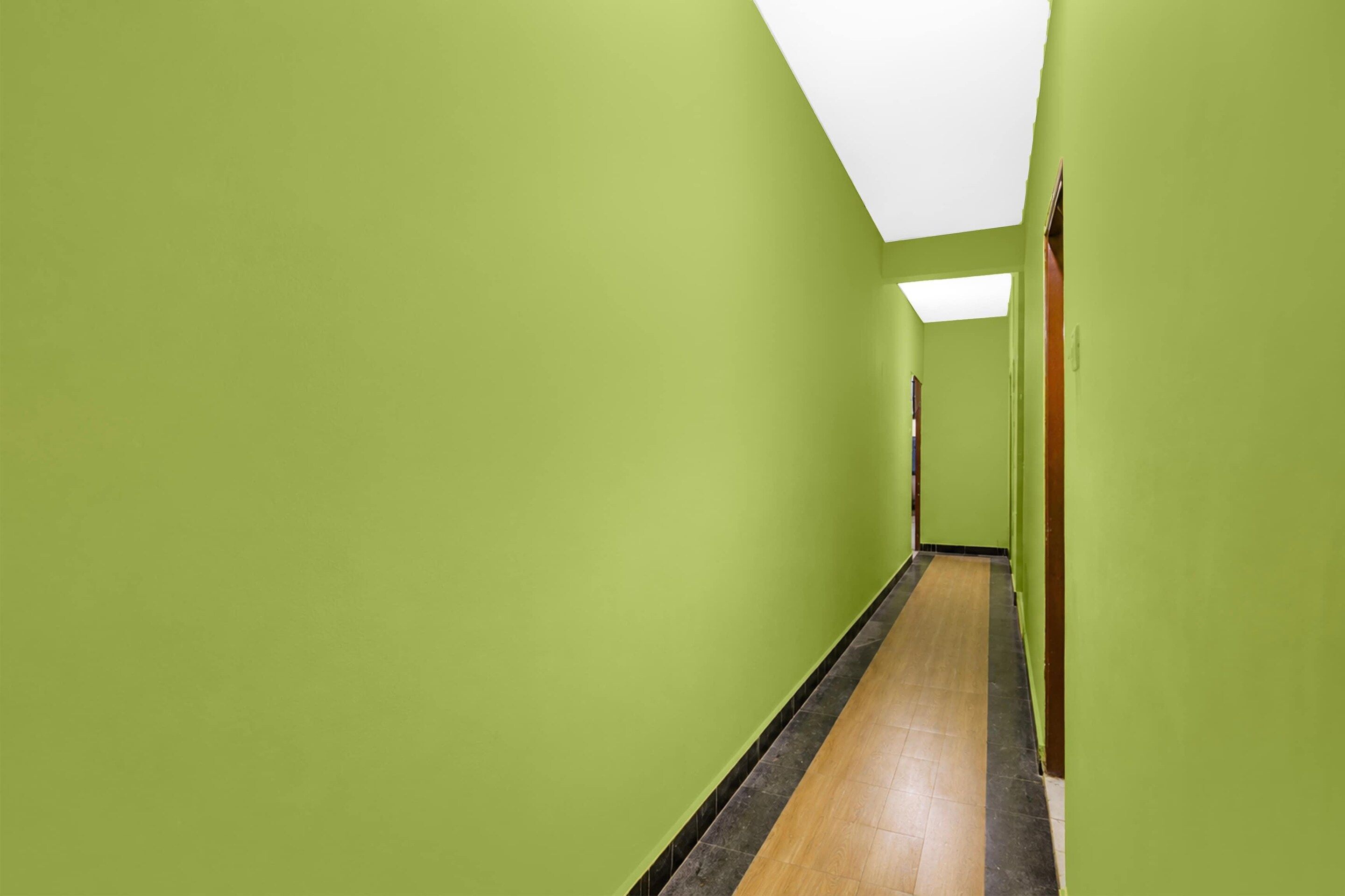 A hallway with green walls and a wooden floor.