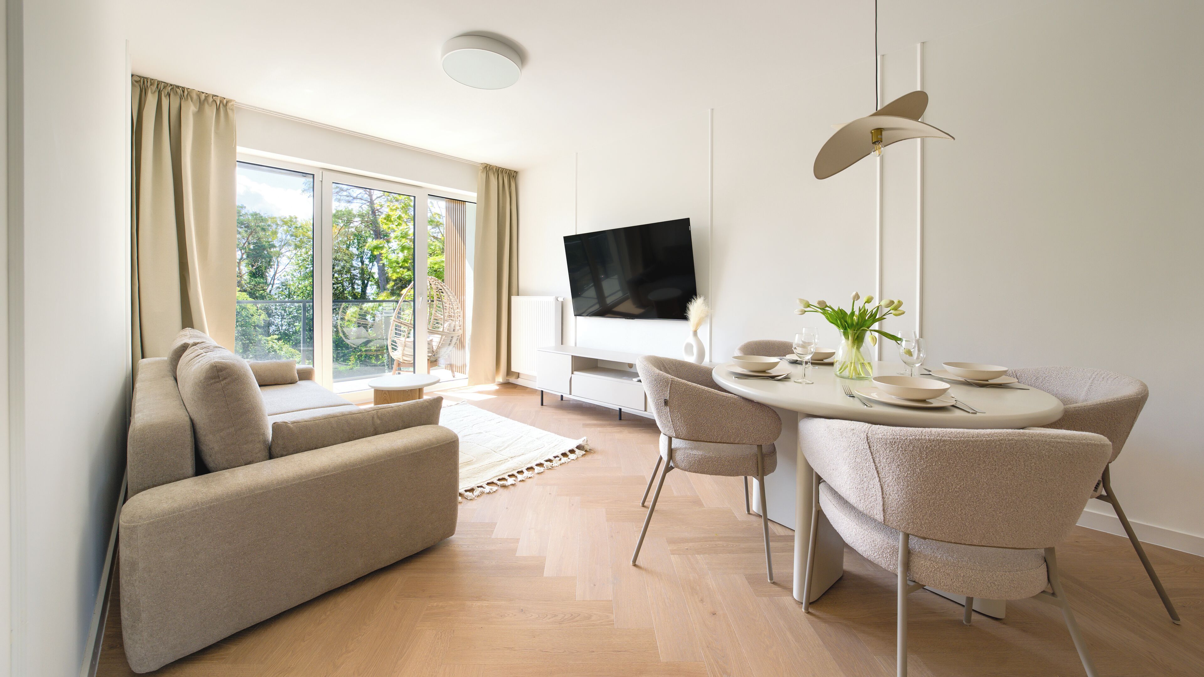 Ein modernes Wohnzimmer mit einer Couch, einem Esstisch, Stühlen und einem Fernseher.