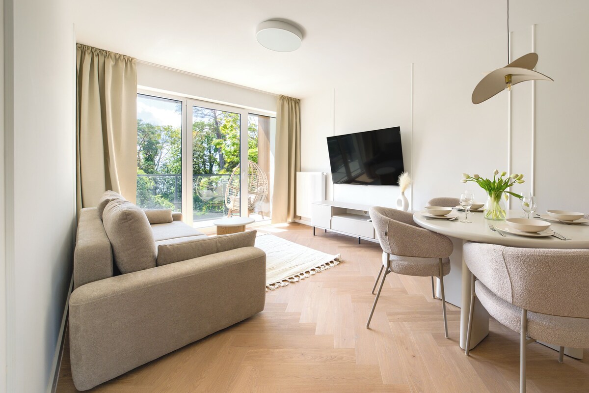 A modern living room with a sofa, dining table, chairs, and a TV.