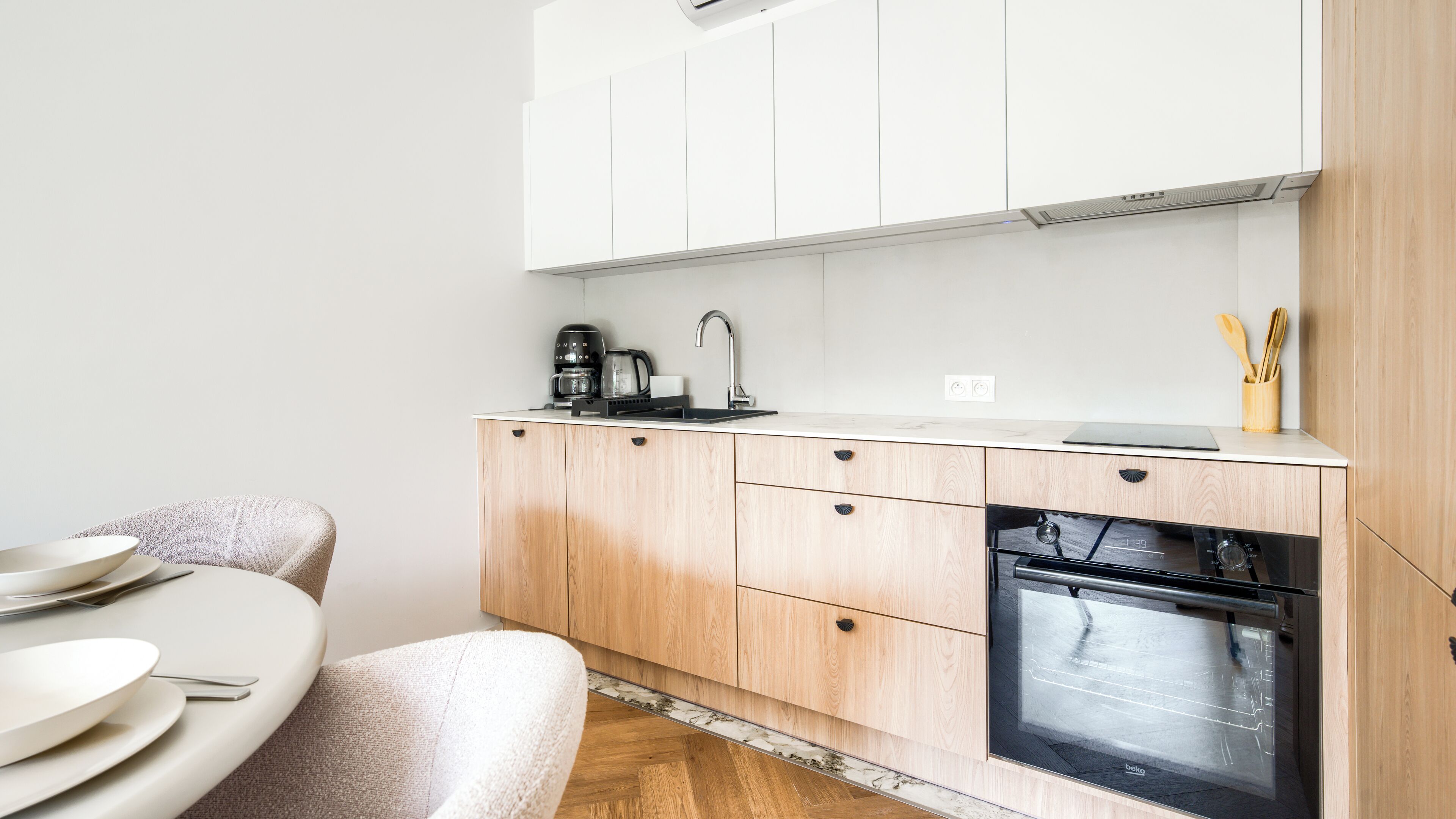 A compact kitchen with a built-in oven, a coffee maker, and a sink.