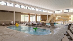 An indoor swimming pool with lounge chairs, a water slide, and a lifeguard stand. - Apartamenty Sun & Snow Koniecznego (Dziwnów)