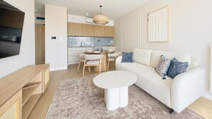 A modern living room with a sofa, coffee table, and a dining area with chairs. - Apartamenty Sun & Snow Koniecznego (Dziwnów)