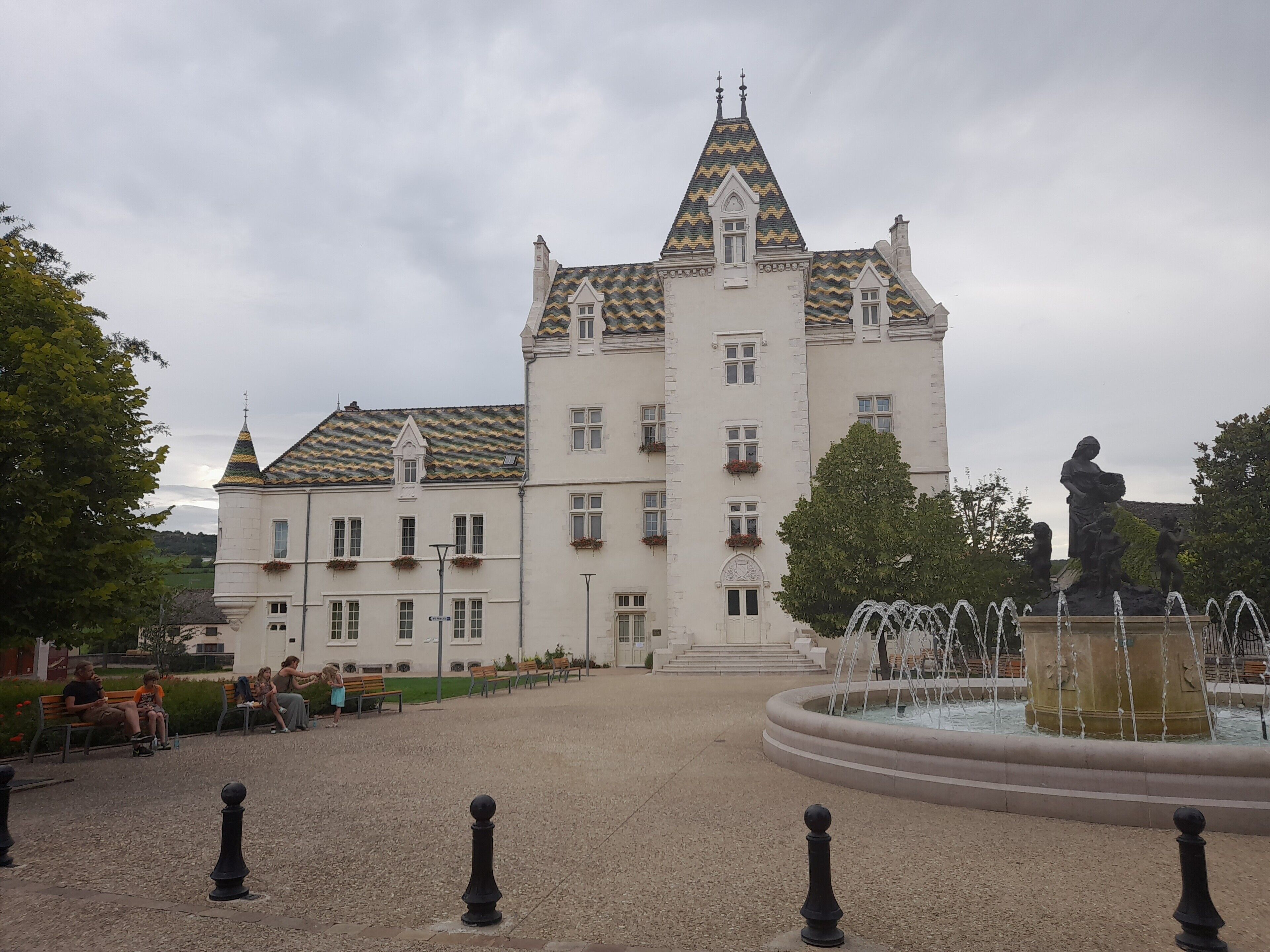 A large building with a symmetrical facade, multiple windows, and a central tower with a pointed roof.