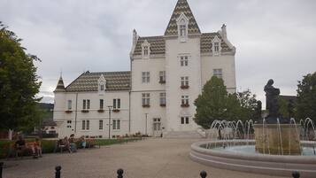 A large building with a symmetrical facade, multiple windows, and a central tower with a pointed roof.