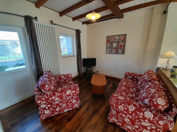 A room with two sofas, a small table, a TV, and a window with curtains.