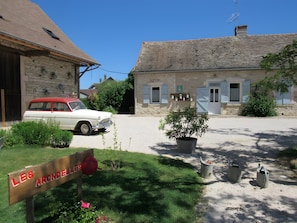 A white car parked in front of a stone building with a sign reading 'LES ARONDELLES'.