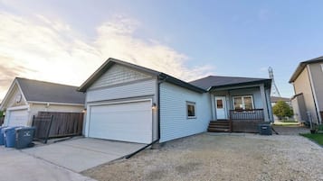 Une propriété résidentielle dotée d’un garage, d’un porche et d’une allée gravillonnée.