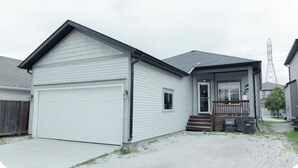 A single-story house with a garage, a front porch, and a small front yard. - Cozy house in luxurious Bridgewater area. (Winnipeg)