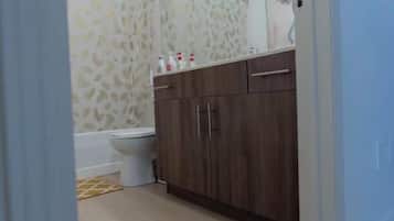 Ein Badezimmer mit Toilette, Holzschränken und einem duschvorhang mit Muster.