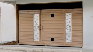 A set of double doors with decorative panels and a small square window. - Classic SGD Lawn And Hotel (Varanasi)