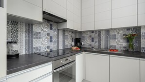 A modern kitchen with patterned backsplash tiles, stainless steel appliances, and a black countertop. - Lumina 3room Apart near Pałac Kultury (Warszawa)