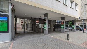 A building entrance with a gated driveway, a sign indicating a no-drug zone, and a poster advertising a concert. - Lumina 3room Apart near Pałac Kultury (Warszawa)