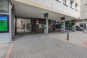 A building entrance with a gated driveway, a sign indicating a no-drug zone, and a poster advertising a concert. - Lumina 3room Apart near Pałac Kultury (Warszawa)