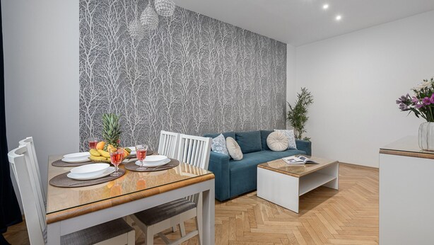 A modern living space with a dining area, a sofa, a coffee table, and a patterned wall. - Lumina 3room Apart near Pałac Kultury (Warszawa)
