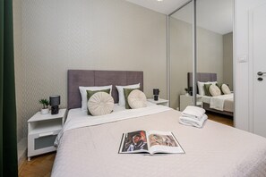 A neatly made bed with a magazine, a bedside lamp, and a nightstand with a plant. - Lumina 3room Apart near Pałac Kultury (Warszawa)